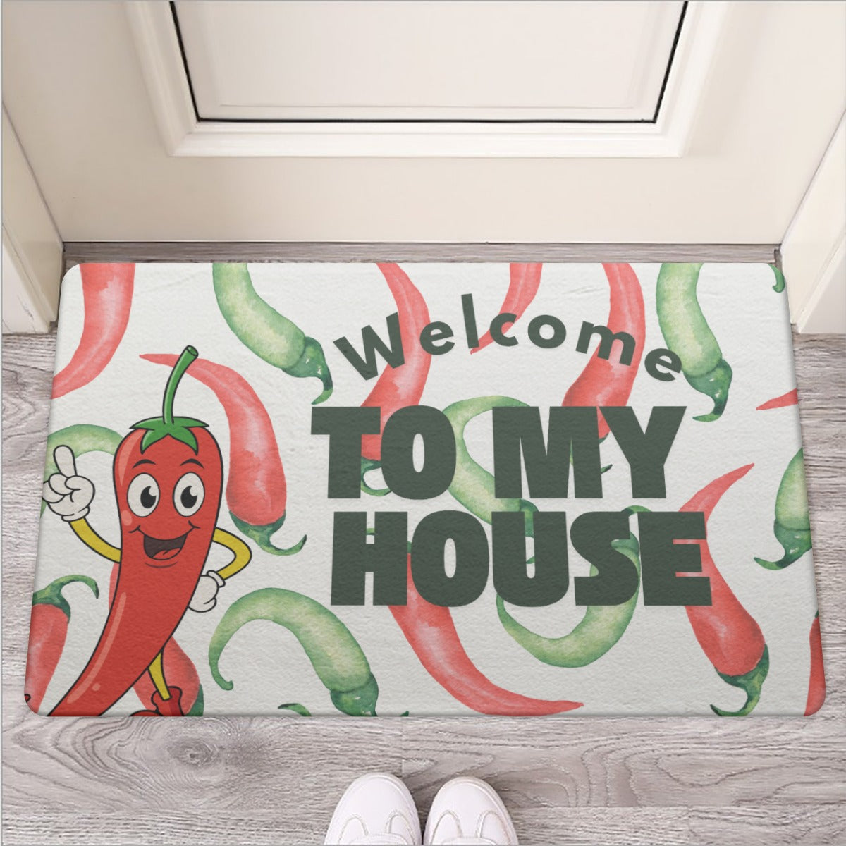 Doormat with cartoon peppers and 'Welcome to my house' text on a wooden floor.